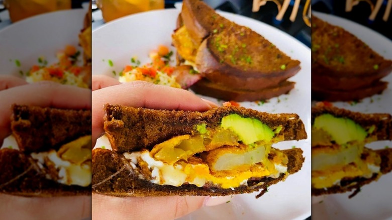 Hand holding half a Southern Slammer with the other half on the plate