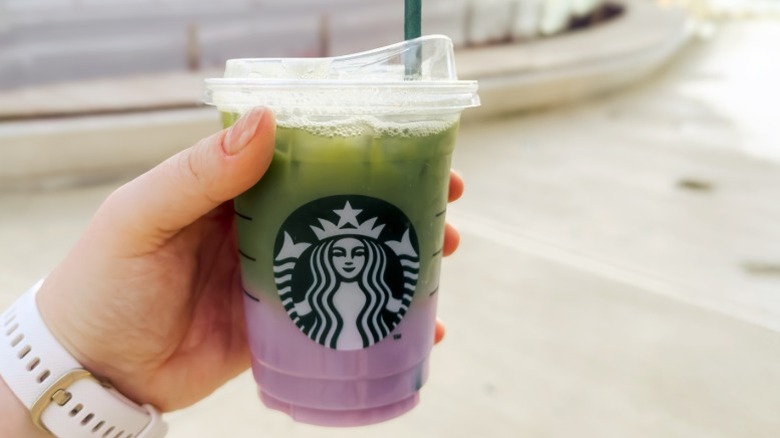 A hand holding a Starbucks Iced Lavender Cream Matcha Latte