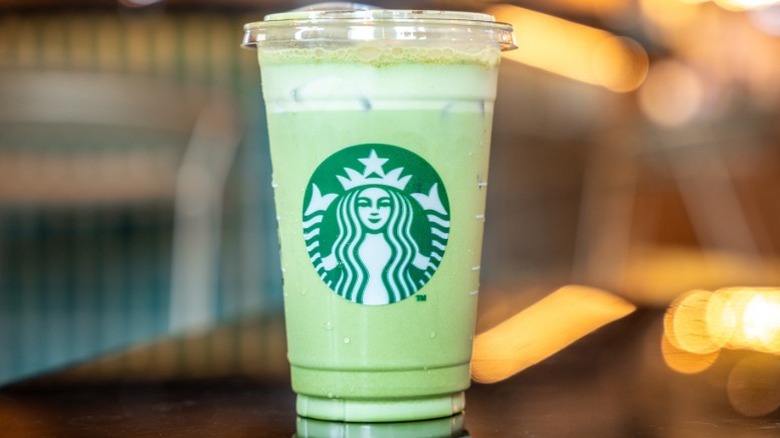An iced Starbucks Matcha Latte in a plastic cup sitting on a table