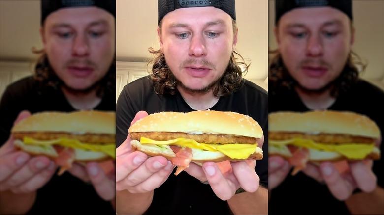 Person holding a Burger King chicken sandwich with bacon, cheese