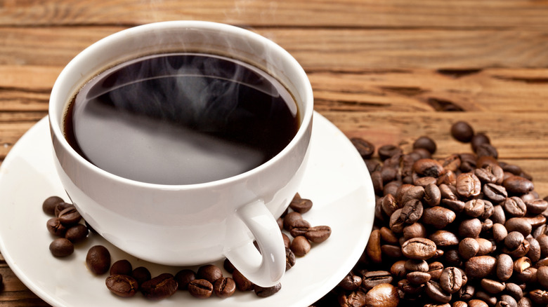 Cup of dark coffee with coffee beans