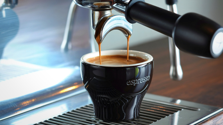 Espresso machine pulling shot of espresso in small black cup