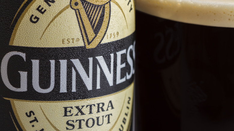 Close-up of logo on bottle of Guinness Extra Stout and pint glass