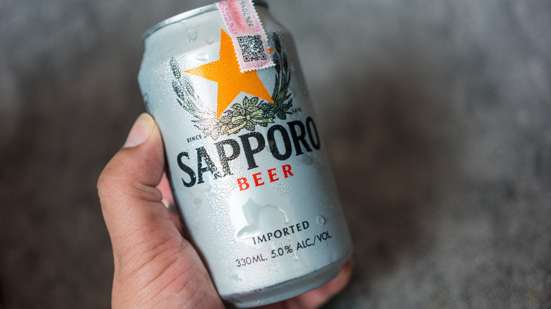 Hand holding a can of Sapporo beer