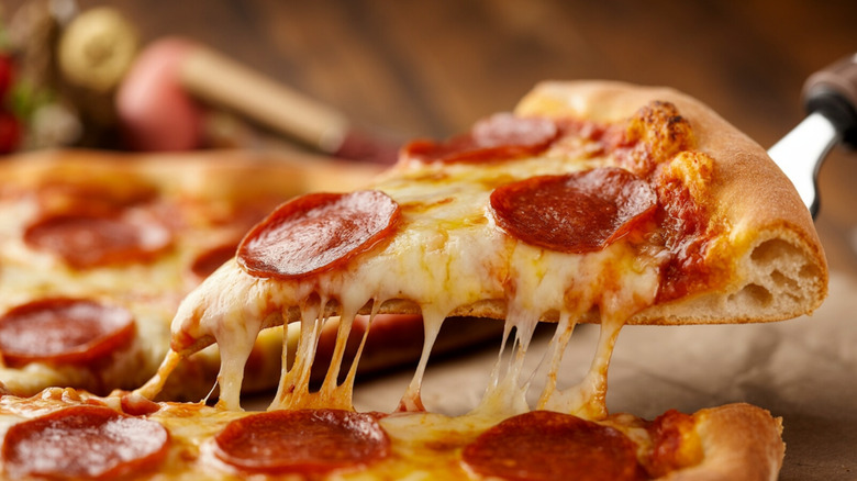 A cheese pull on a slice of pepperoni pizza.