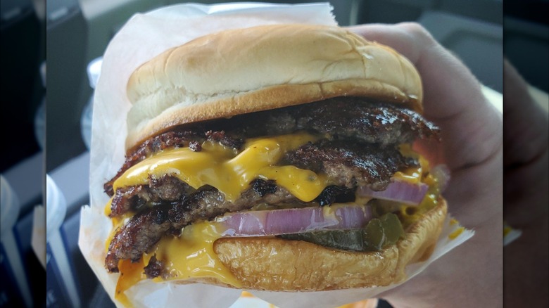 Someone holding a triple patty ButterBurger with The Works from Culver's