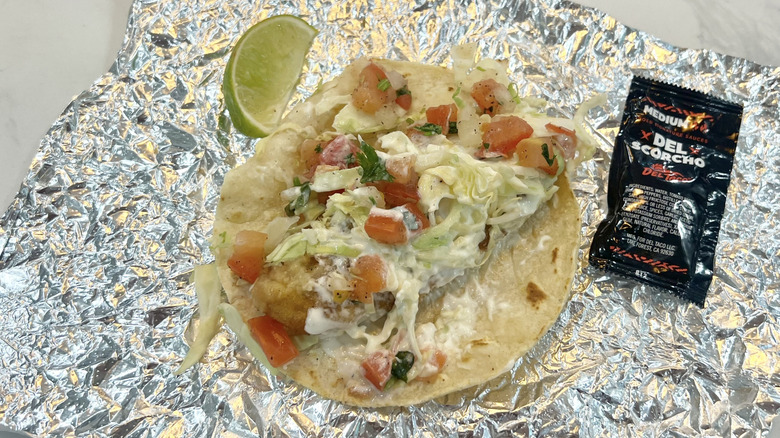 Del Taco Beer Battered Fish Taco with lime and sauce.
