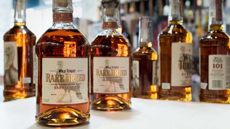Two bottles of Rare Breed placed on a table with other bottles of Wild Turkey shown with a blurred background