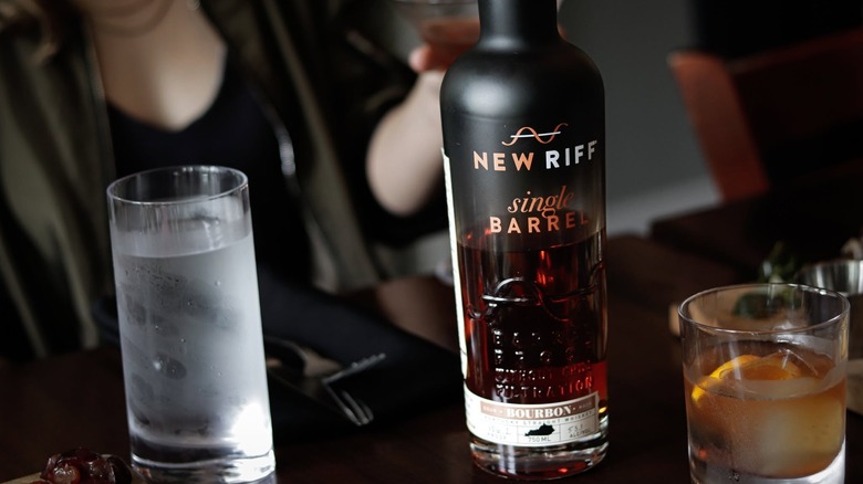 A bottle of New Riff Single Barrel on a table with a person shown in a blurred background