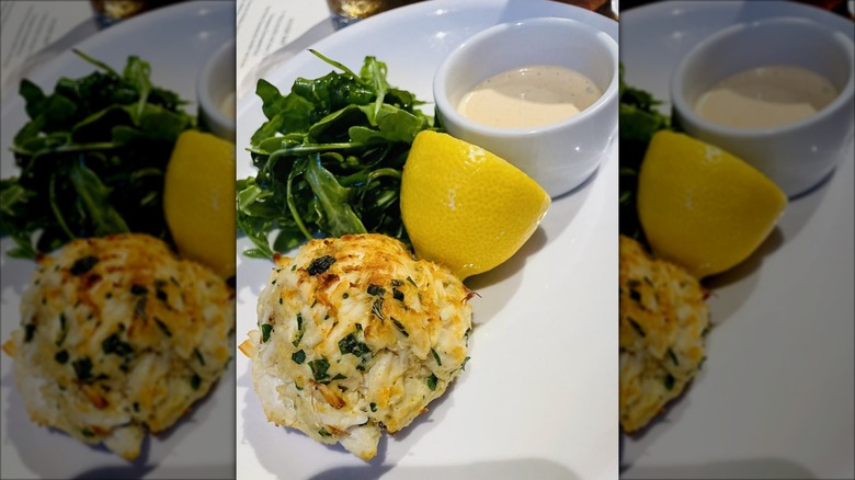 Crab cake with lemon, sauce, and greens