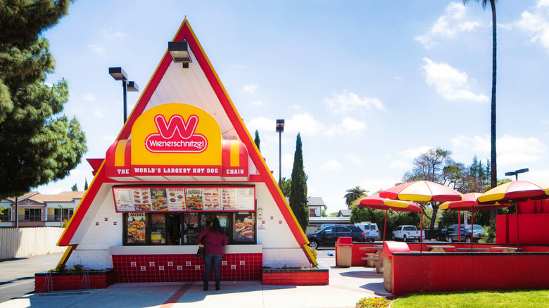 Triangular Wienerschnitzel Hot Dog restaurant with outside seating against blue sky