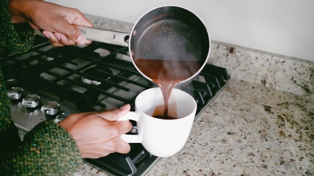 Close-up of unrecognizable black woman pouring hot chocolate into mug