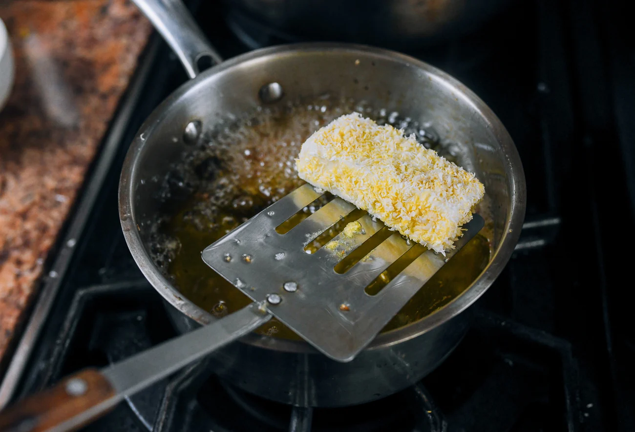 dropping breaded milk pudding into hot oil