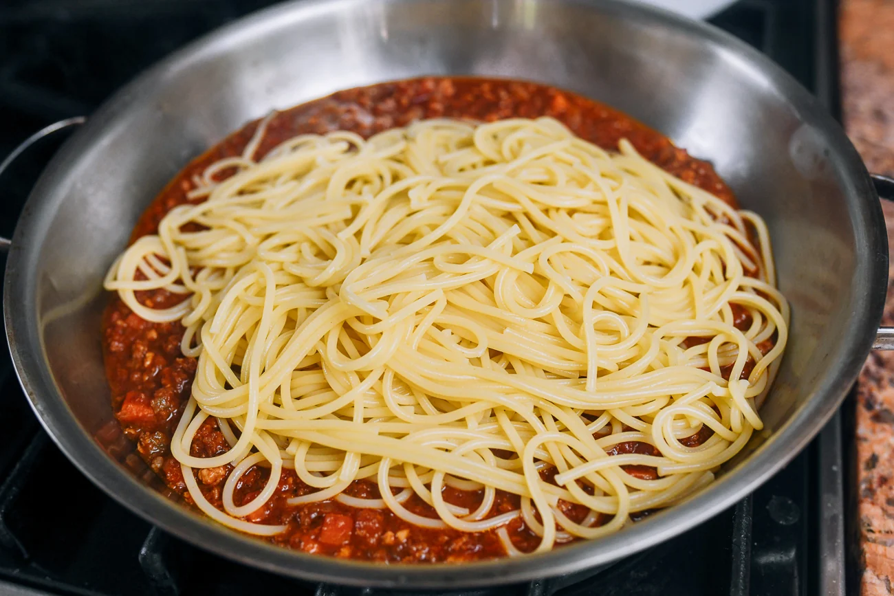 combining spaghetti with bolognese sauce