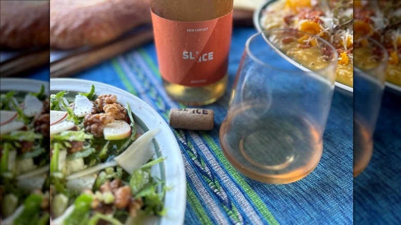 Bottle and glass of Slice Skin Contact White Wine next to salad
