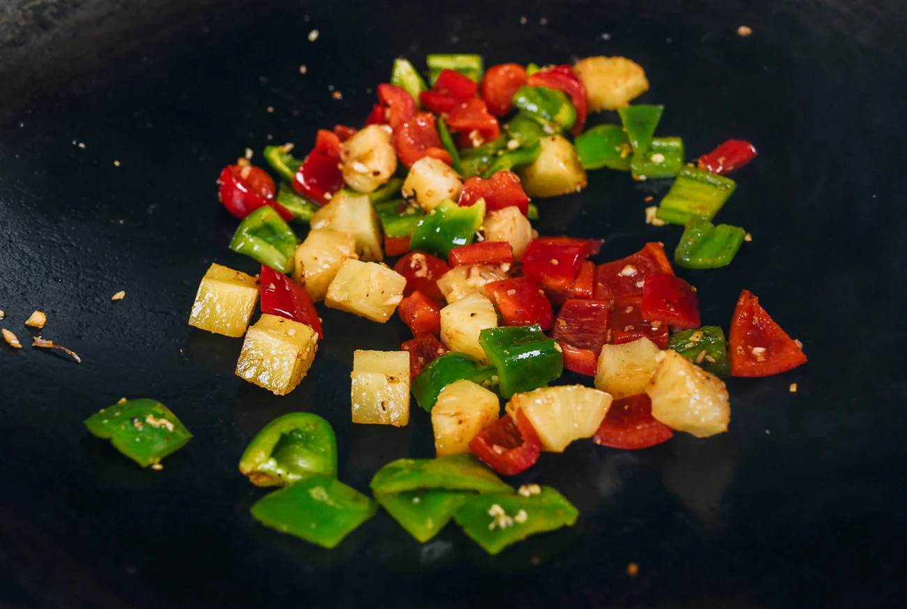 stir-frying peppers and pineapple chunks