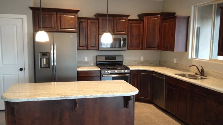 A kitchen with River White granite countertops and dark wood cabinetry