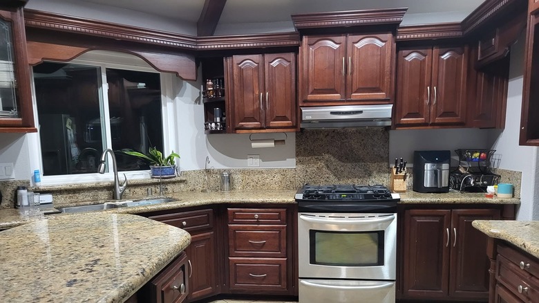 A kitchen with Kashmir White granite countertops and deep cherry wood cabinets