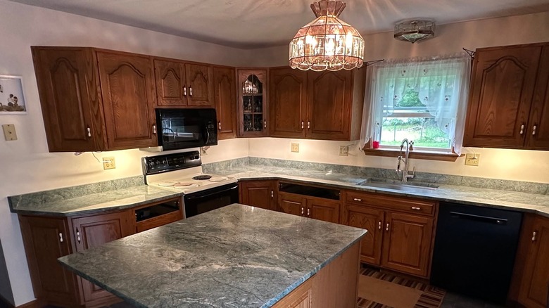 A spacious kitchen with beautiful green Costa Esmeralda granite countertops and island and golden maple cabinets